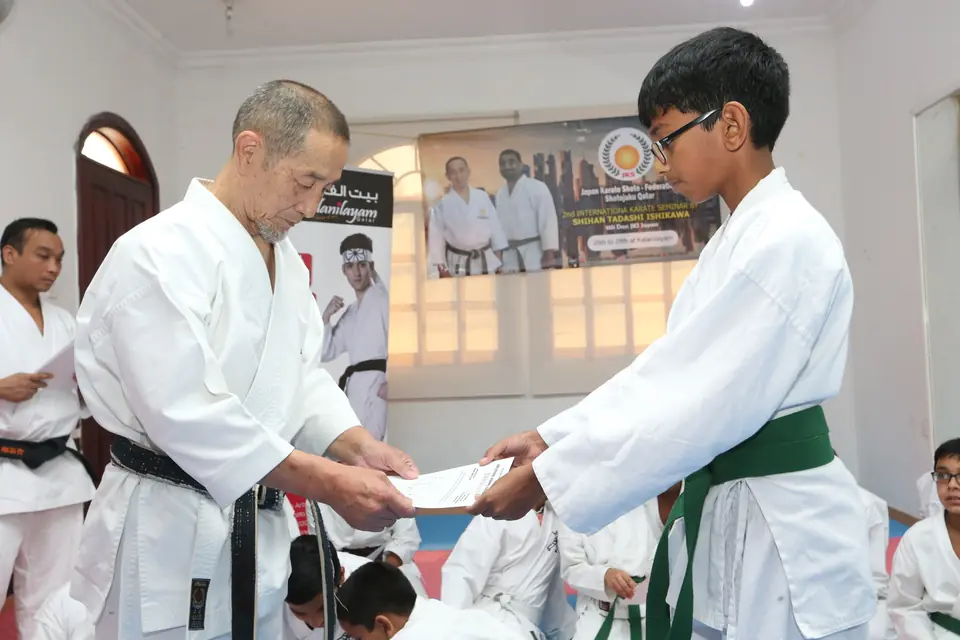 Student receiving a belt grading certificate from the sensei