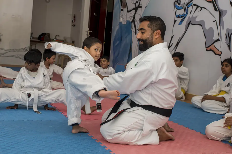 Sensei Najmal Ibrahim coaching a young student's kick while the class watches